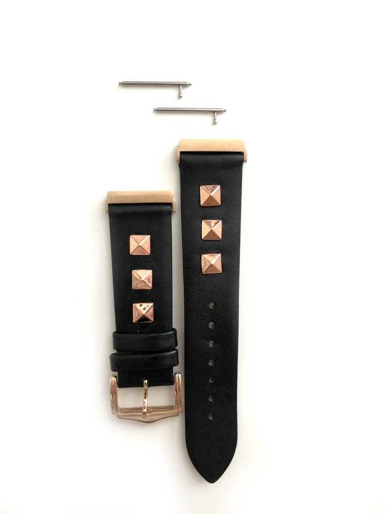 May include: Black leather watch band with rose gold accents and pyramid-shaped studs. The band has a buckle closure and comes with two spring bars.