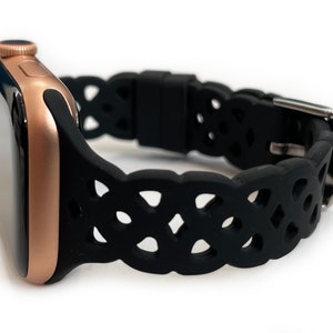 May include: A rose gold Apple Watch with a black silicone band featuring a Celtic knot design.