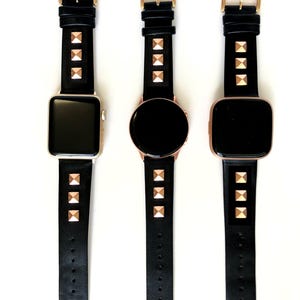 May include: Three black leather watch bands with gold pyramid-shaped studs. The bands are shown on three different smartwatches.
