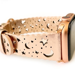 May include: Rose gold Apple Watch band with a cut-out design of stars and moons.
