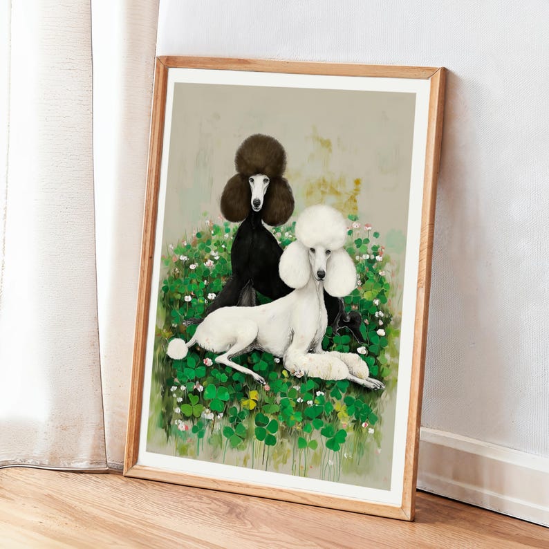 May include: A framed art print featuring two poodles. One poodle is black, the other is white, and they are set against a backdrop of green foliage and small white flowers. The artwork has a soft, painterly style and is displayed in a wooden frame.