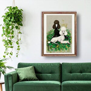 May include: A framed print featuring two poodles, one black and one white, amidst a field of green and white flowers. The black poodle stands, while the white poodle reclines. The artwork has a vintage aesthetic and is displayed on a white wall.