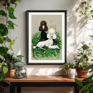May include: A framed art print featuring two poodles. One poodle is black, the other is white, both with fluffy fur. They are set against a backdrop of green foliage and white flowers. The artwork is displayed on a wooden surface.
