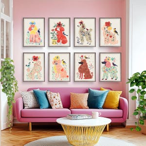 Puede incluir: Ocho impresiones artísticas enmarcadas con ilustraciones de caniches coloridos adornados con flores y pájaros. Los caniches se representan en varios colores, incluyendo rosa, rojo y beige, sobre un fondo neutro. La obra de arte se exhibe sobre un sofá rosa.