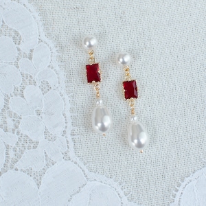 May include: A pair of dangle earrings with red square-shaped gemstones and white pearl drops.