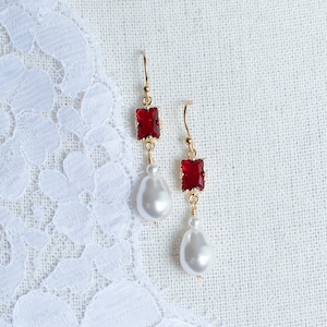 May include: A pair of gold earrings with red square-shaped gemstones and white pearl drops.