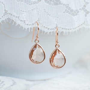 May include: Rose gold teardrop earrings with clear faceted crystals.