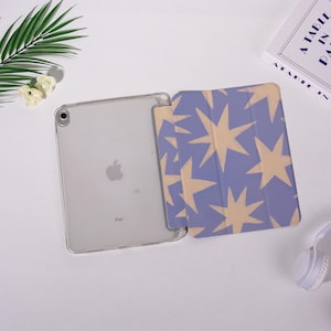 K&ouml;nnte beinhalten: Ein iPad in einer transparenten H&uuml;lle mit einer blauen und beigefarbenen Sternmuster-Abdeckung. Das iPad ist ge&ouml;ffnet und zeigt den Bildschirm. Die Abdeckung ist ge&ouml;ffnet und zeigt ein sich wiederholendes Sterndesign. Der Hintergrund ist wei&szlig;.