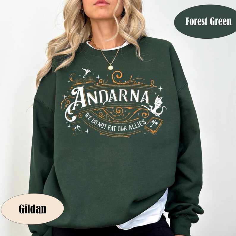 May include: Forest green sweatshirt with the word "Andarna" in a decorative font, along with the phrase "We do not eat our allies." The design includes stylized illustrations of dragons and other fantasy elements. The sweatshirt is a Gildan brand.