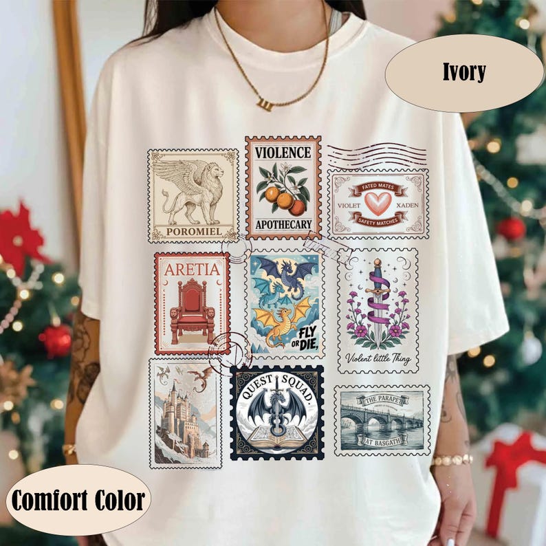 K&ouml;nnte beinhalten: Elfenbeinfarbenes T-Shirt mit einer Reihe von Briefmarken-Designs zum Thema Fantasy. Die Briefmarken zeigen einen Greif, einen Drachen, ein Schloss und Texte wie "Violence Apothecary" und "Quest Squad". Das T-Shirt ist mit "Comfort Color" gekennzeichnet.