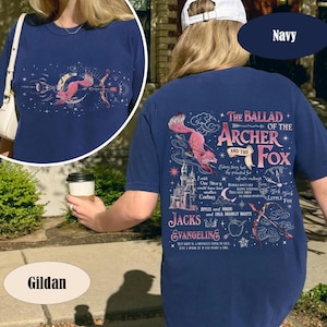 May include: Navy blue t-shirt with a graphic design featuring a pink fox, bow and arrow, and text that reads "The Ballad of the Archer and the Fox." The shirt is made by Gildan.
