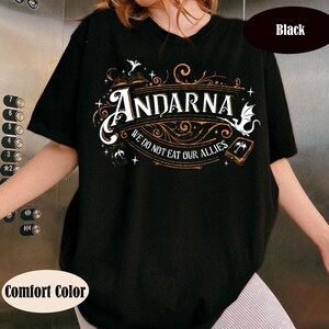 May include: Black t-shirt with the word "ANDARNA" in a decorative font, along with the phrase "WE DO NOT EAT OUR ALLIES." The design includes illustrations of a dragon, a book, and other fantasy elements. The shirt is labeled "Comfort Color."