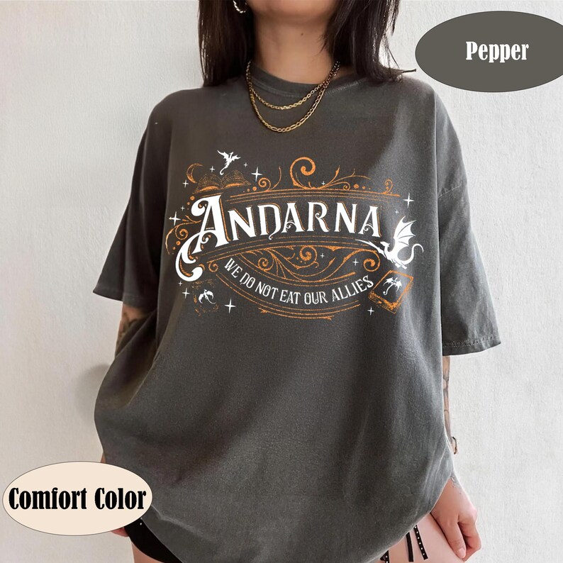 May include: A dark gray t-shirt with the word "ANDARNA" in a decorative font, with the text "WE DO NOT EAT OUR ALLIES" below. The shirt has a vintage look, with a comfort color. The shirt is a unisex style.