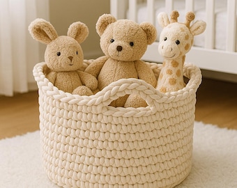 May include: A woven cream-colored basket holds three plush toys: a bunny, a bear, and a giraffe. The toys are light brown and tan, with embroidered facial features. The basket has two handles and sits on a white rug.