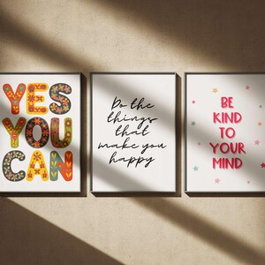 May include: Three framed art prints with inspirational quotes. The first says "YES YOU CAN" in colorful, floral-patterned letters. The second says "Do the things that make you happy." The third says "BE KIND TO YOUR MIND."