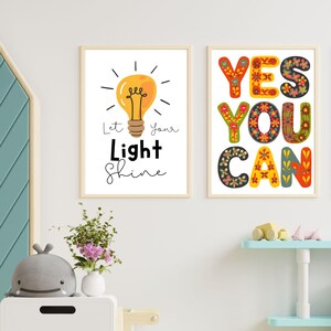 May include: Two framed art prints with inspirational quotes. One features a yellow lightbulb with the text "Let Your Light Shine." The other print says "YES YOU CAN" in colorful, floral-patterned letters. Both are in light wood frames.