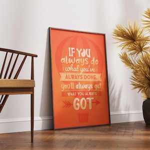May include: An orange framed poster with the text "IF YOU always do what you've ALWAYS DONE, you'll always get WHAT YOU ALWAYS GOT". A wooden chair and decorative dried plants in black vases are also visible.