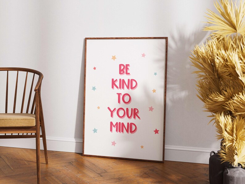 May include: A framed poster with the words "BE KIND TO YOUR MIND" in pink, surrounded by colorful star illustrations. The poster has a wooden frame and is displayed against a white wall.