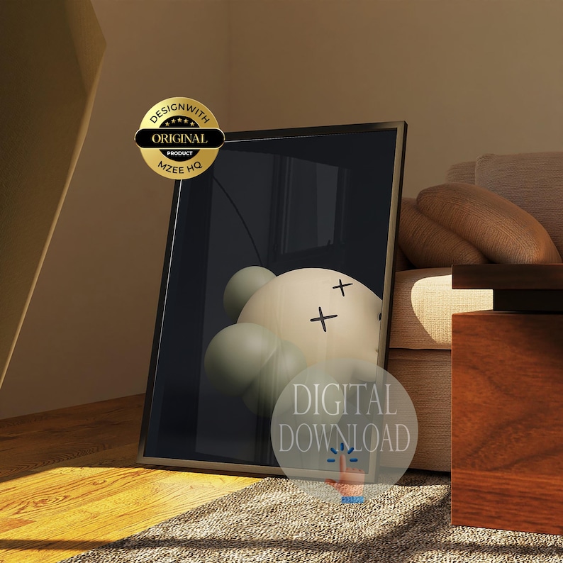May include: A framed rectangular wall art print featuring a cream-colored circular character with two black X-shaped eyes and several rounded sage green shapes clustered around the base, set against a dark background with a gold seal and text.
