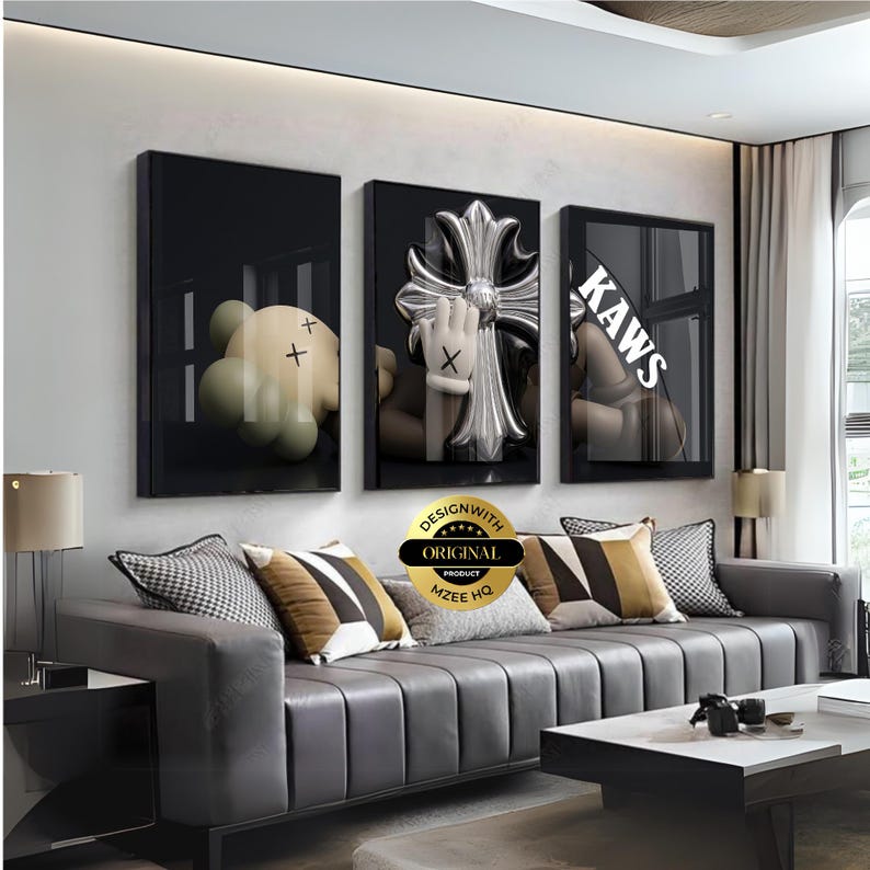 May include: A set of three rectangular wall art prints with black frames. The left print shows a tan character with X-shaped eyes. The centre print features a silver metallic cross and a hand with X-shaped eyes. The right print displays the text KAWS.
