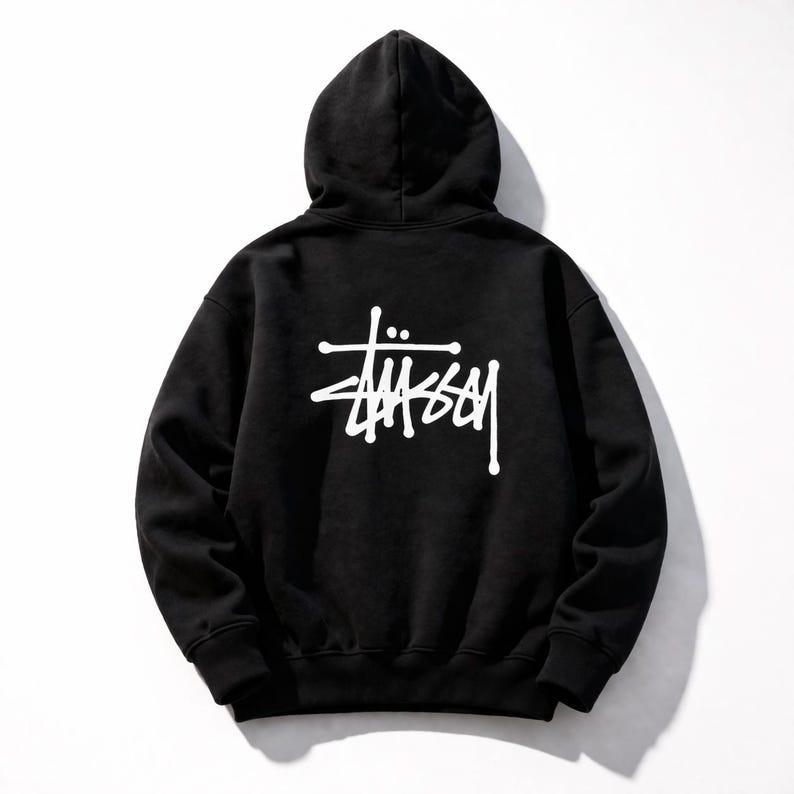 May include: Black hooded sweatshirt with the white "St&uuml;ssy" logo on the back. The hoodie has a drawstring and a kangaroo pocket. The sweatshirt is made of a soft, comfortable material.