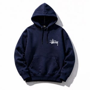 May include: Navy blue hooded sweatshirt with a white logo on the chest. The sweatshirt features a drawstring hood and a kangaroo pocket. The Stussy logo is in a handwritten style. The garment is made of a soft, comfortable material.