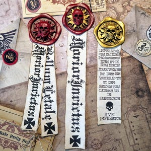 Puede incluir: Un surtido de marcadores y sellos de estilo pergamino con diseños de calaveras y cruces. Los marcadores presentan letras góticas y cruces. Los sellos son rojos y dorados, con el texto "LiselleMade Purity Seal" visible.