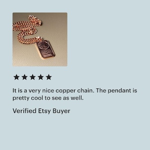 Puede incluir: Un collar de cadena de metal color cobre con un colgante rectangular. El colgante tiene grabado un dise&ntilde;o gr&aacute;fico y el texto COPPER, junto con un texto m&aacute;s peque&ntilde;o debajo. La cadena consta de eslabones ovalados entrelazados a juego.