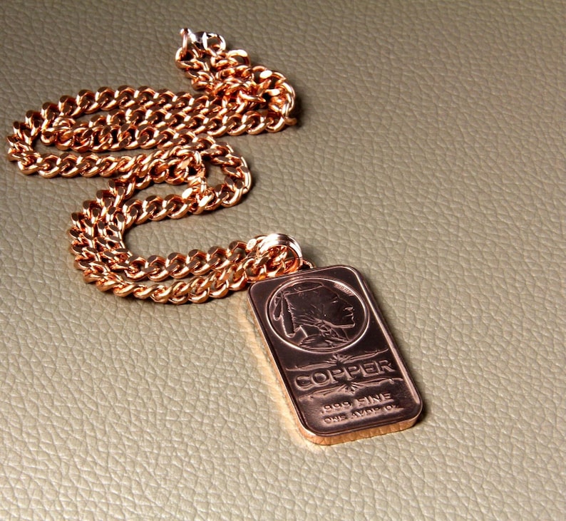 A heavy Copper Curb chain necklace with a copper pendant. The pendant is rectangular and has an embossed Indian head and the words 'COPPER 999 FINE ONE AVOIR. OZ' engraved on it. All of the findings are handmade with solid copper wire.