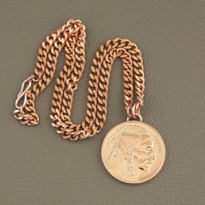 Solid copper necklace with a copper buffalo pendant. The chain is a cuban link style. The pendant features a detailed profile of a Native American with the word LIBERTY visible.  The necklace is a stylish and unique piece of jewelry.