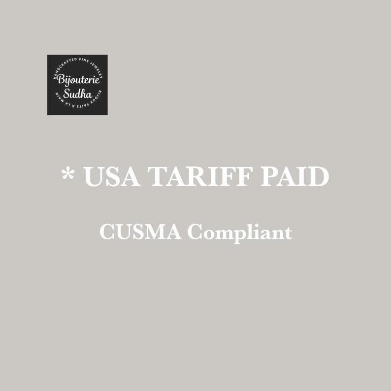 May include: A pale grey background with white text reading "* USA TARIFF PAID" and "CUSMA Compliant". A black square with white text that reads "Bijouterie Sudha" is in the upper left corner.