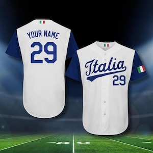May include: White baseball jersey with blue sleeves. The jersey features the word "Italia" in blue script, the number 29, and the Italian flag. The back of the jersey has the number 29 and space for a name.