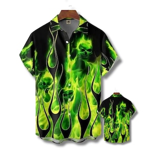 May include: Short-sleeved button-up shirt with a black background and a vibrant green flame and skull design. The shirt features a classic collar and button closure. A smaller version of the shirt is also visible.