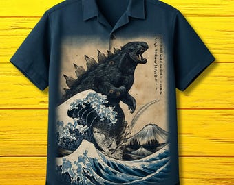 May include: Navy blue short-sleeve button-down shirt featuring a Godzilla graphic in the style of a Japanese woodblock print. The artwork depicts Godzilla emerging from a wave with Mount Fuji in the background. The shirt has a classic collar.