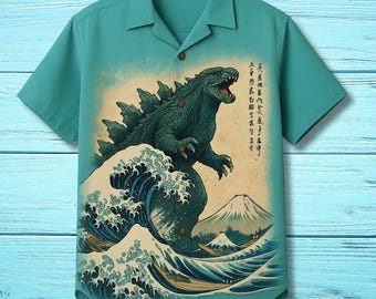 May include: Teal short-sleeve button-up shirt featuring a Godzilla graphic in the style of a Japanese woodblock print. The design includes a large wave, Mount Fuji, and Japanese text. The shirt has a classic collar and wooden buttons.