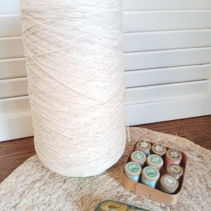 Può includere: Una grande rocca di filo color bianco sporco con la parte superiore verde, una piccola scatola di legno contenente otto rocchetti di filo in miniatura di vari colori pastello e una scatola di metallo rettangolare con l'etichetta "Le Fil Au Chinois".