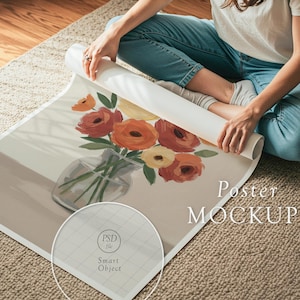 May include: A rolled-up poster mockup featuring a floral painting in a glass vase. The artwork showcases orange, red, and yellow flowers. The poster is on a beige surface, with the words "Poster MOCKUP" visible.