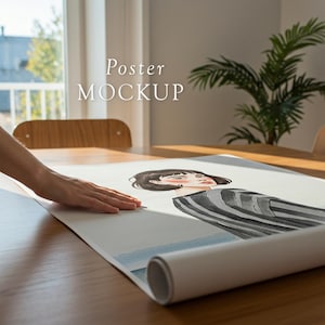 May include: A poster mockup featuring a watercolour illustration of a person with short dark hair wearing a striped shirt. The poster is rolled up and being held by a hand on a wooden table.