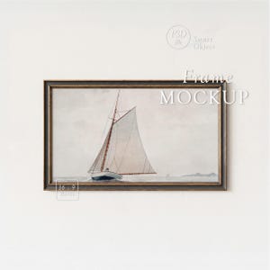 May include: A framed watercolor painting of a sailboat on the water. The artwork features a white sail, a blue hull, and a dark wooden frame. The words "Frame MOCKUP" are displayed on the image.