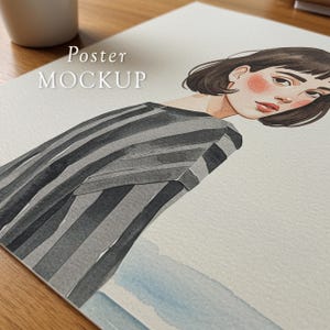 May include: Watercolor illustration of a person with short dark hair and rosy cheeks, wearing a gray and black striped top. The artwork is on a white paper, with the words "Poster MOCKUP" printed on the top left.