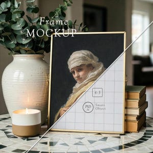May include: A gold metal frame mockup with a painting of a woman wearing a headscarf. The frame is propped up on a mosaic tile table next to a vase with greenery, a candle, and a stack of books. The text "Frame Mockup" is at the top.
