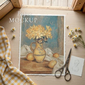 May include: A still life painting featuring a yellow pitcher with yellow flowers, lemons, and a white cloth. The words "Paper MOCKUP" are printed on the top left. A yellow and white checkered cloth, scissors, and a sketch are also present.