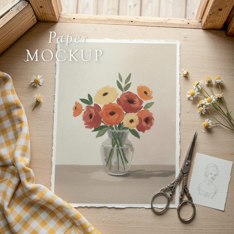 May include: A floral art print featuring a bouquet of orange and yellow flowers in a clear glass vase. The print is on textured paper, with the words "Paper MOCKUP" at the top. A pair of scissors and a sketch are next to the print.
