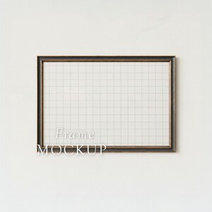 May include: A rectangular frame with a dark brown border and a grid pattern inside. The text "Frame MOCKUP" is displayed in white letters at the bottom of the frame. The frame is set against a white background.