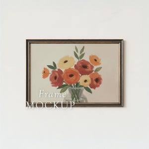 May include: A framed floral art print featuring a bouquet of orange, yellow, and red flowers in a glass vase. The artwork is set against a neutral background, with the words "Frame MOCKUP" in white text. The frame is dark brown.