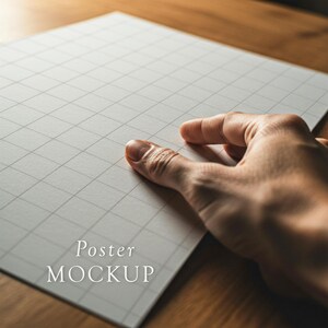 Pode incluir: Uma m&atilde;o repousa sobre um papel quadriculado branco com o texto "Poster MOCKUP". O papel, com um padr&atilde;o de grade subtil, est&aacute; sobre uma superf&iacute;cie de madeira. A ilumina&ccedil;&atilde;o cria sombras suaves.