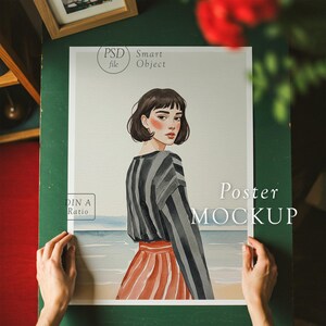 K&ouml;nnte beinhalten: Ein Poster-Mockup mit einer Aquarellillustration einer Frau mit dunklen Haaren, die ein gestreiftes Hemd und einen rot-wei&szlig; gestreiften Rock tr&auml;gt. Der Hintergrund ist ein Aquarellbild einer Strandszene. Der Text "Poster MOCKUP" ist auf dem Poster gedruckt.