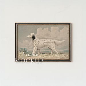 May include: A framed print featuring a white dog with black spots, set against a backdrop of a cloudy sky and grassy terrain. The artwork is in a dark brown frame, with the words "Frame MOCKUP" at the bottom.