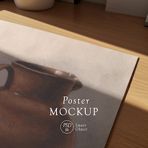 May include: A poster mockup featuring a brown ceramic jug illustration. The poster has the words "Poster MOCKUP" in a serif font. The image also includes a "PSD file" and "Smart Object" logo.