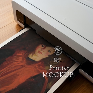 May include: A white printer is shown printing a piece of art. The artwork features a portrait of a person in a red garment. The text "Printer MOCKUP" is visible on the printed page. The image is a mockup.